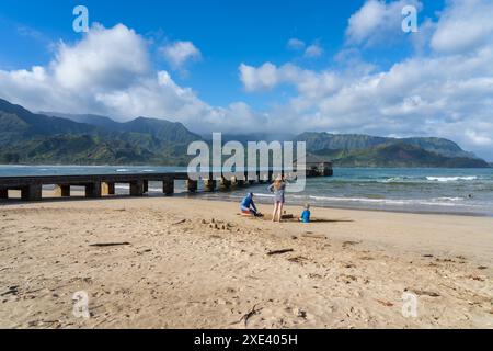 Kauai, HI, États-Unis - 28 janvier 2024 : les gens sur la plage avec Hanalei Pier en arrière-plan, Kauai, Hawai, États-Unis. Banque D'Images