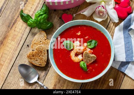 Soupe de Saint-Valentin maison, cuisine festive. Gazpacho de purée de soupe de tomates avec tomates servies fruits de mer sur une table en bois rustique. Copier sp Banque D'Images