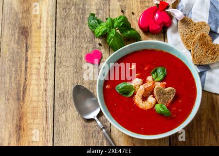 Soupe de Saint-Valentin maison, cuisine festive. Gazpacho de purée de soupe de tomates avec tomates servies fruits de mer sur une table en bois rustique. Copier sp Banque D'Images