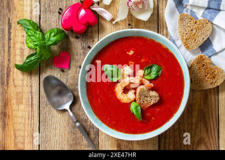 Soupe de Saint-Valentin maison, cuisine festive. Gazpacho de purée de soupe de tomates avec tomates servies fruits de mer sur une table en bois rustique. Top vie Banque D'Images