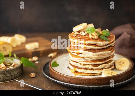 Célébration de la journée des crêpes, petit déjeuner américain. Délicieuses crêpes à la banane maison avec des noix et du caramel sur une table en bois rustique. Co Banque D'Images