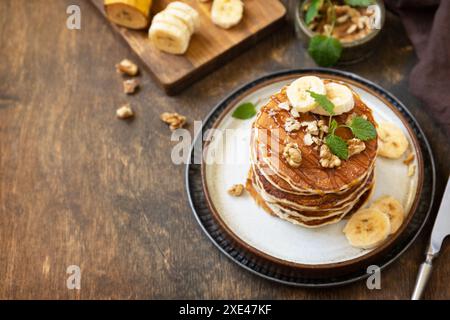Célébration de la journée des crêpes, petit déjeuner américain. Délicieuses crêpes à la banane maison avec des noix et du caramel sur une table en bois rustique. Co Banque D'Images