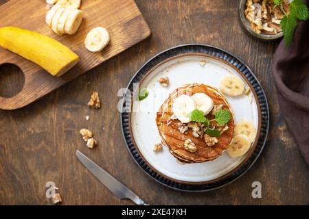 Célébration de la journée des crêpes, petit déjeuner américain. Délicieuses crêpes à la banane maison avec des noix et du caramel sur une table en bois rustique. À Banque D'Images
