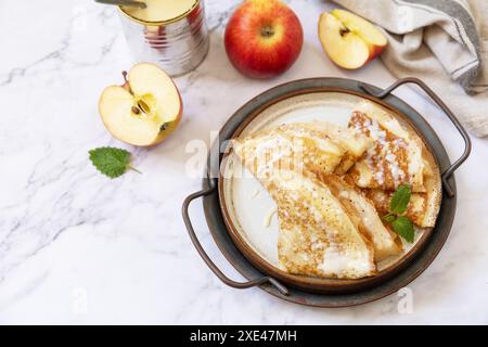 Célébration de la journée des crêpes, petit déjeuner sain. Crêpes sucrées maison avec pommes et lait condensé sur une table en marbre. Copier spac Banque D'Images