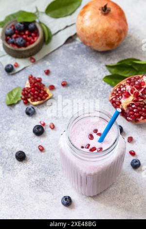 Smoothie protéiné végétalien à base de grenade et de myrtille sur une table en pierre. Nourriture saine. Style de vie bien-être. Foodisme, rawis Banque D'Images