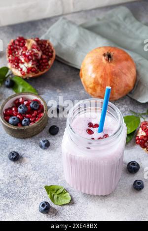 Smoothie protéiné végétalien à base de grenade et de myrtille sur une table en pierre. Nourriture saine. Style de vie bien-être. Foodisme, rawis Banque D'Images