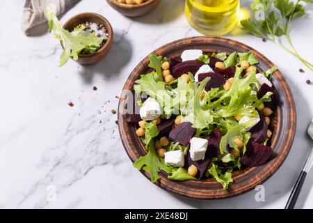 Salade de betterave printanière saine avec épinards, feta au fromage et pois chiches sur une table en marbre. Copier l'espace. Banque D'Images