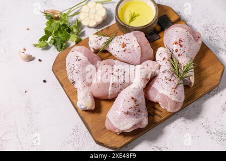 Viande de poulet. Des pilons de poulet frais crus aux épices sur un plan de coupe en laine sur un comptoir en pierre. Copier l'espace. Banque D'Images