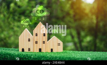 Environnement propre, concept de protection de l'environnement, Un modèle de maison en bois sur fond vert et une icône de symbole de réduction de dioxyde de carbone, carbone CRE Banque D'Images