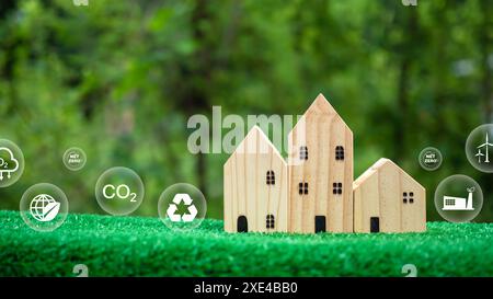 Un modèle de maison en bois sur un fond vert et une icône de symbole de réduction de dioxyde de carbone, crédit carbone, zéro net, concept de réduction des émissions de CO2, propre Banque D'Images