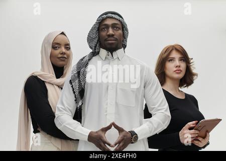 Homme d'affaires arabe se tient confiant aux côtés de deux femmes d'affaires, dépeignant une équipe solide et diversifiée qui incarne l'ambition, Banque D'Images