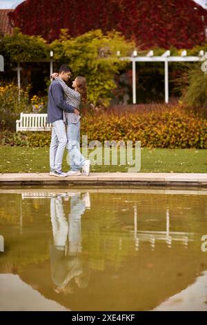 Jeune couple embrassant et se réjouit au lac. charmant jeune couple s'embrassant à l'extérieur en automne. Couple d'amour marchant dans la nature. Banque D'Images