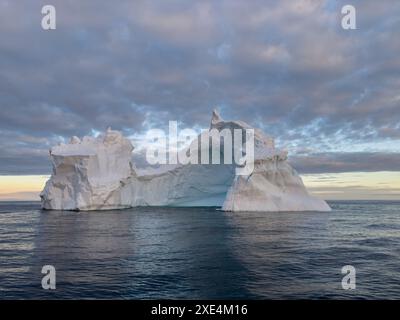 Un énorme glacier sécessionniste haut dérive dans l'océan austral au large de la côte de l'Antarctique au coucher du soleil, la péninsule Antarctique, le S. Banque D'Images