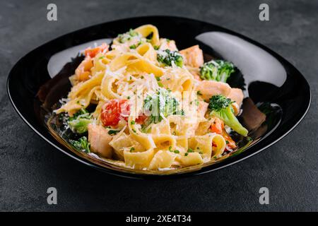 Plat italien de pâtes fettuccine alfredo avec saumon grillé et brocoli Banque D'Images