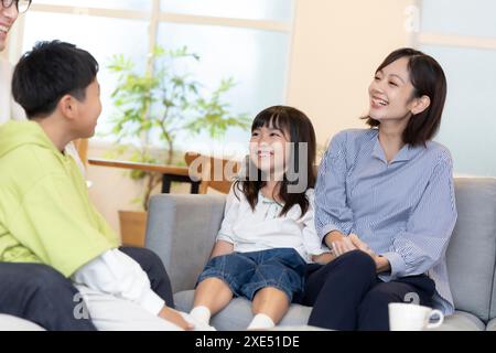 Famille de quatre personnes face à face sur un canapé Banque D'Images