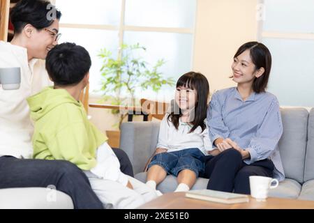 Famille de quatre personnes face à face sur un canapé Banque D'Images