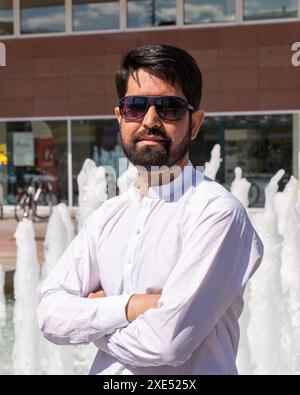 Portrait en gros plan d'un pakistanais moderne avec une barbe sombre, des vêtements légers et des lunettes de soleil Banque D'Images