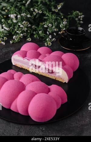 Gâteau mousse de framboise contemporain sur assiette noire Banque D'Images