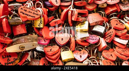 Vérone, Italie - juin 2022 : fond de serrures en forme de coeur sur un mur, symbole de l'amour pour toujours. Banque D'Images