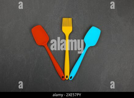 Spatules culinaires en silicone et pinceaux sur noir Banque D'Images