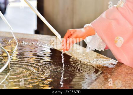 Temple Senso-ji mains d'Une femme purifiant ses mains à l'abreuvoir Banque D'Images