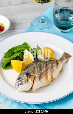 Dorade grillée avec légumes et légumes verts sur une table en bois Banque D'Images