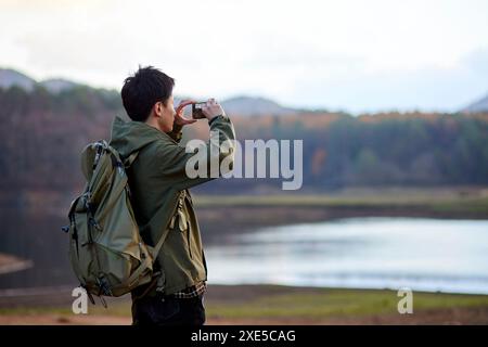 Jeune japonais prenant des photos avec son smartphone Banque D'Images