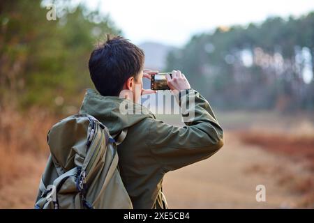 Jeune japonais prenant des photos avec son smartphone Banque D'Images