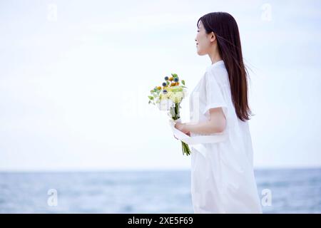 Jeune femme japonaise portant une robe et tenant un bouquet de fleurs Banque D'Images