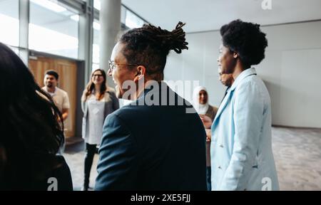 Groupe diversifié de professionnels engagés dans la conversation lors d'un événement de réseautage dans un espace de bureau moderne. Démontrer un sentiment de connexion et col Banque D'Images