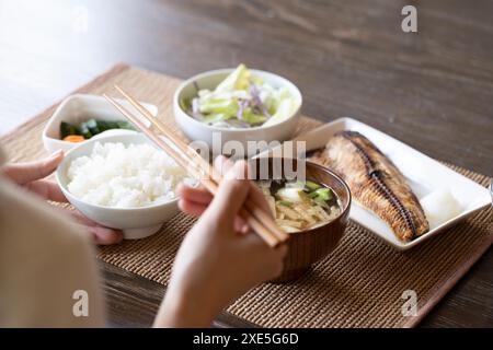 Jeune femme mangeant le petit déjeuner à la main Banque D'Images