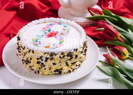 Gâteau blanc décoré de crème près des tulipes rouges Banque D'Images