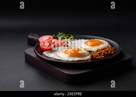 Délicieux petit déjeuner copieux composé de deux œufs au plat, de lentilles en conserve et de microgreens Banque D'Images