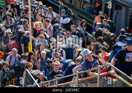 Les fêtards arrivent à la gare de Castle Cary alors qu'ils sortent de la plate-forme et prennent les bus qui les fermeront vers Glastonbury Festival à Worthy Farm dans le Somerset. Date de la photo : mercredi 26 juin 2024. Banque D'Images