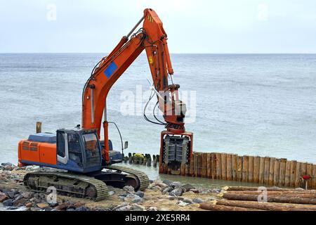 Machine de battage de pieux sur la plage sur le bord de mer. Travaux de stabilisation du littoral Banque D'Images