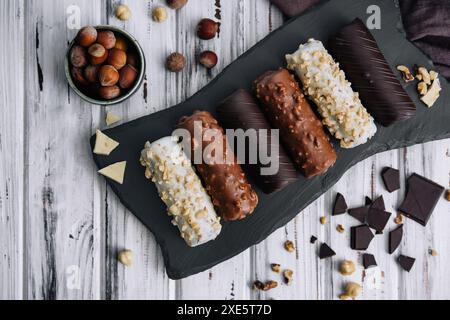 Dessert français éclairs ou profiteroles avec différents glaçons au chocolat sur une assiette en pierre noire Banque D'Images