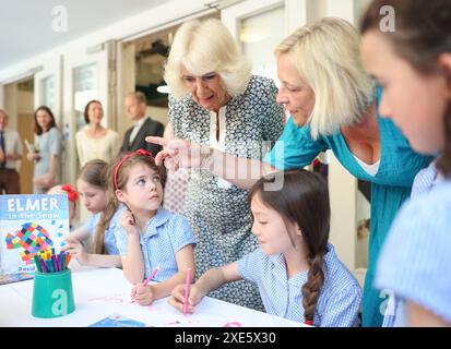 La reine Camilla rend visite à une classe d'accueil et entend parler de l'initiative de lecture 'Shepherd and Sheep', qui attribue les nouveaux élèves de la réception à un élève de 6e année, qui agit comme une amie et un modèle tout au long des nouveaux élèves de première année à l'école, lors de sa visite à Christ Church C of E Primary School à Londres. Date de la photo : mercredi 26 juin 2024. Banque D'Images