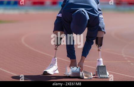 Les athlètes handicapés se préparent en position de départ prêts à courir sur la piste du stade Banque D'Images