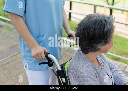 Travailleuse de la santé poussant le fauteuil roulant d'une femme âgée Banque D'Images