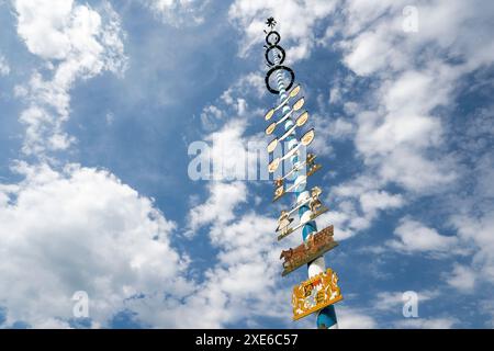 Maypole sur la place du village de Schoenram. Haute Bavière, Allemagne. Le poteau est peint dans les couleurs bavaroises de blanc et bleu et décoré d'emblèmes représentant l'artisanat et l'industrie locale Banque D'Images