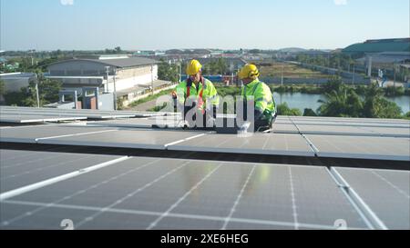 Les deux techniciens installent des panneaux solaires sur le toit de l'entrepôt pour transformer l'énergie solaire en énergie électrique pour nous Banque D'Images