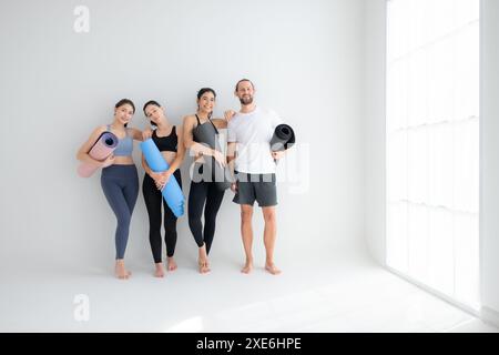 Un groupe d'athlètes féminins et masculins se sont levés et ont bavardé à l'amiable dans le studio avant de commencer le cours de yoga. Banque D'Images