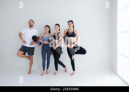 Un groupe d'athlètes féminins et masculins se sont levés et ont bavardé à l'amiable dans le studio avant de commencer le cours de yoga. Banque D'Images