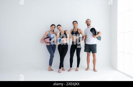 Un groupe d'athlètes féminins et masculins se sont levés et ont bavardé à l'amiable dans le studio avant de commencer le cours de yoga. Banque D'Images