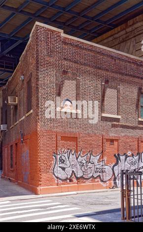 NYC Chinatown : des pairs humoristiques découpés d'une fenêtre en briques au 72-80 Henry Street, un établissement du Département de l'assainissement sous le pont de Manhattan. Banque D'Images