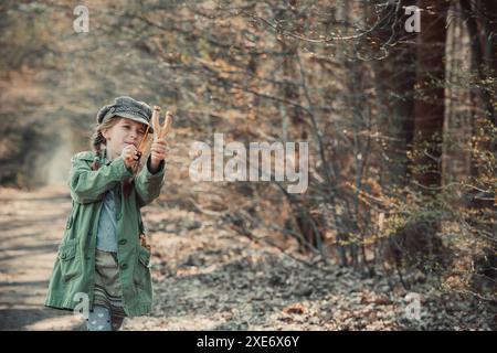 petite fille jouant avec une fronde dans les bois, photo dans le style vintage Banque D'Images