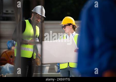 Ingénieur et architecte travaillant sur le chantier de construction, revérifiant les plans et le processus. Banque D'Images