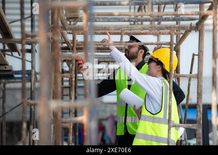 Ingénieur et architecte travaillant sur le chantier de construction, revérifiant les plans et le processus. Banque D'Images