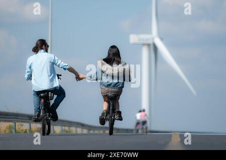 Vue arrière d'une jeune femme faisant du vélo avec son petit ami sur la route Banque D'Images