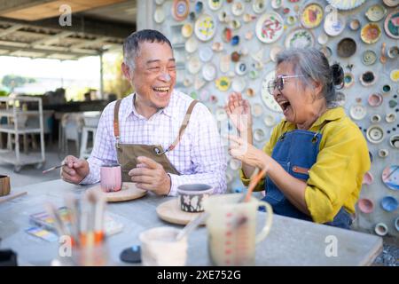 Dans l'atelier de poterie, un couple de retraités asiatiques est engagé dans des activités de fabrication de poterie et de peinture d'argile. Banque D'Images